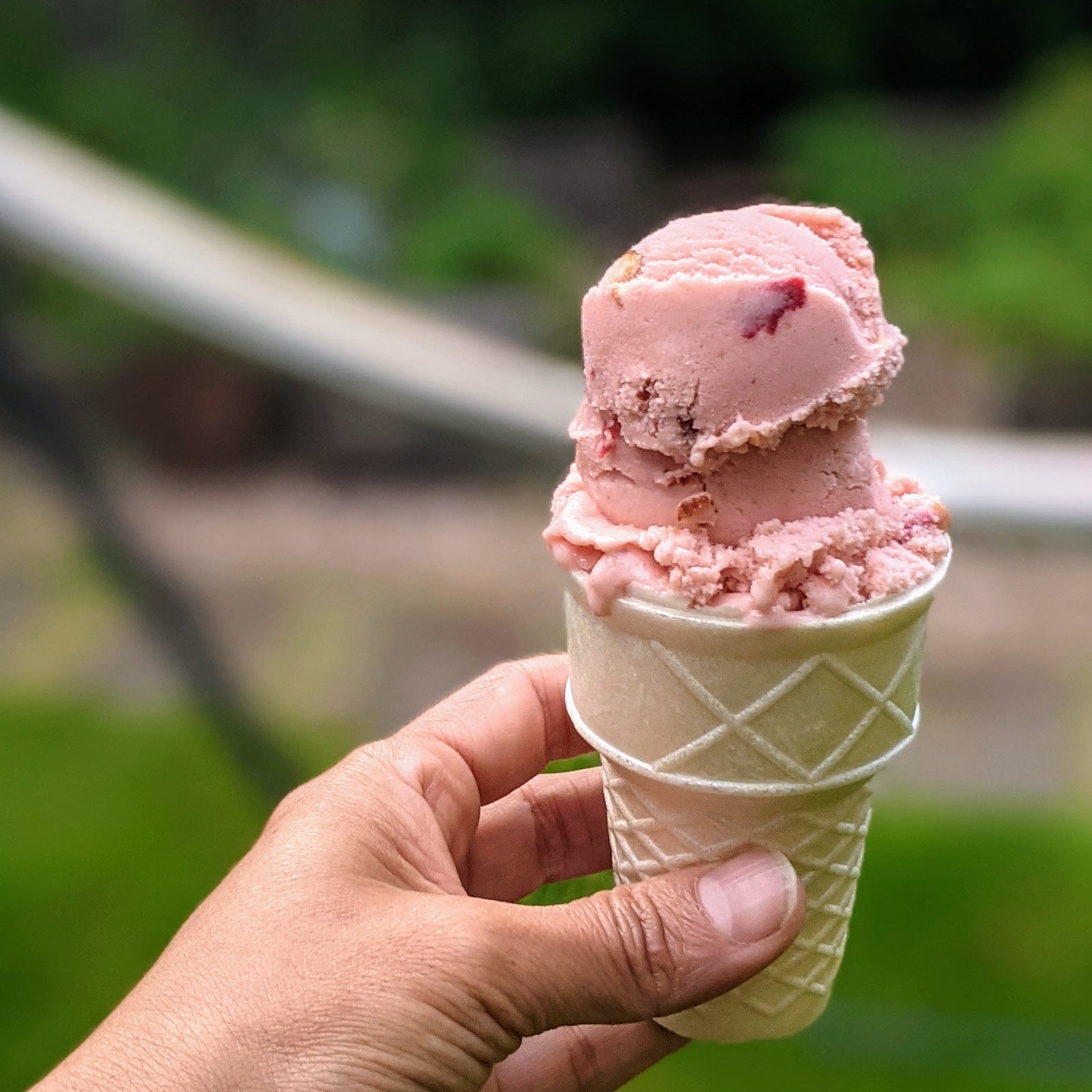 Hand holding an ice cream cone outdoors