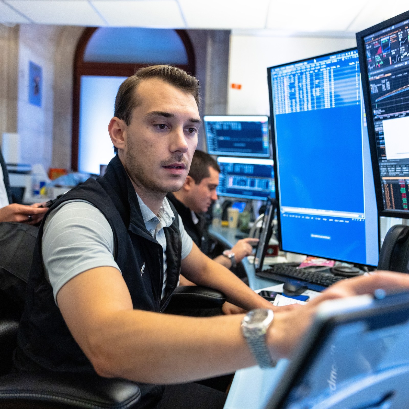 Traders at a multi-monitor desk, testing automated trading strategies before risking money