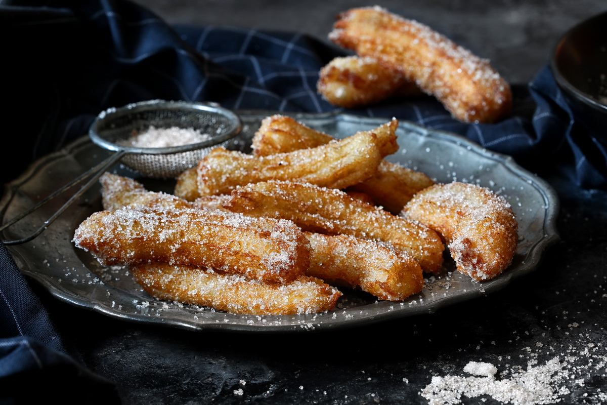Golden sugar-dusted churros on a rustic plate