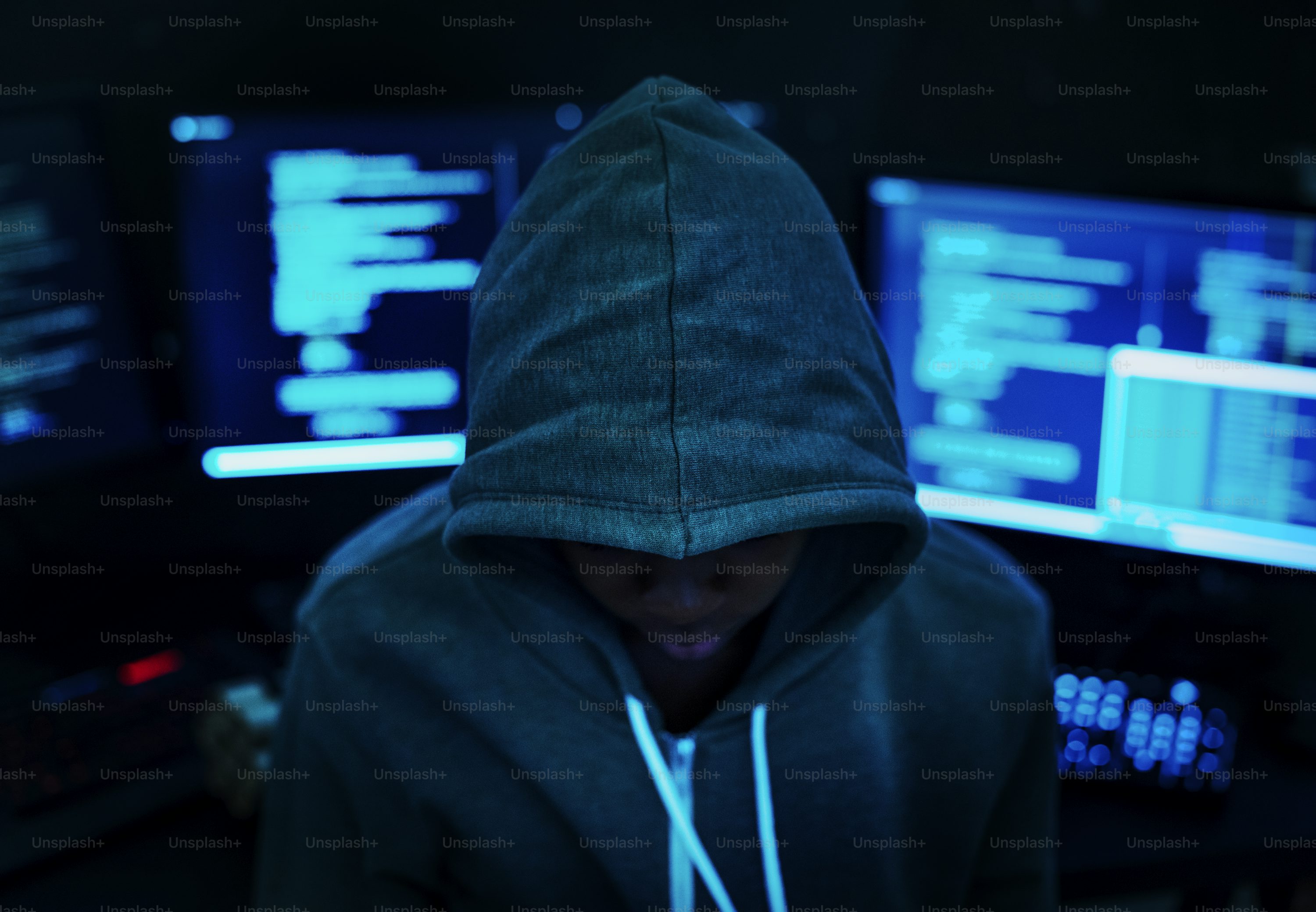 A hooded figure lit by trading screens, the anonymous face behind most AI stock scams