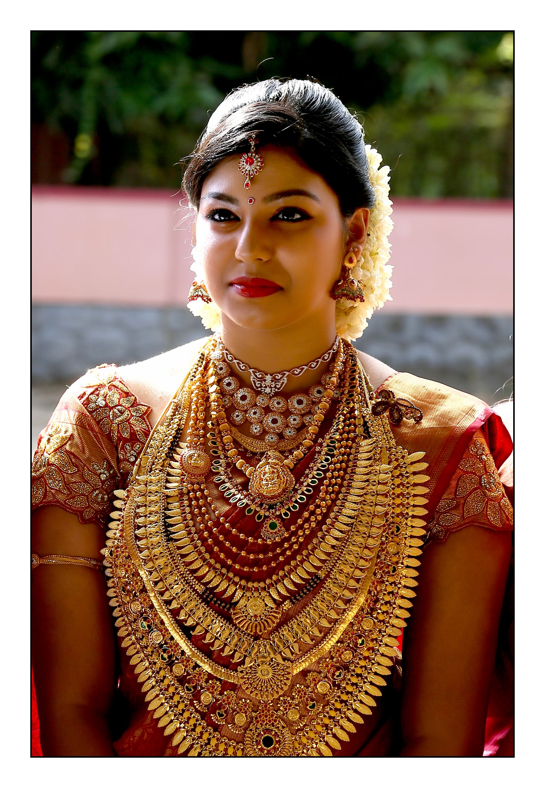 South Indian bride in red silk saree wearing abundant gold jewellery