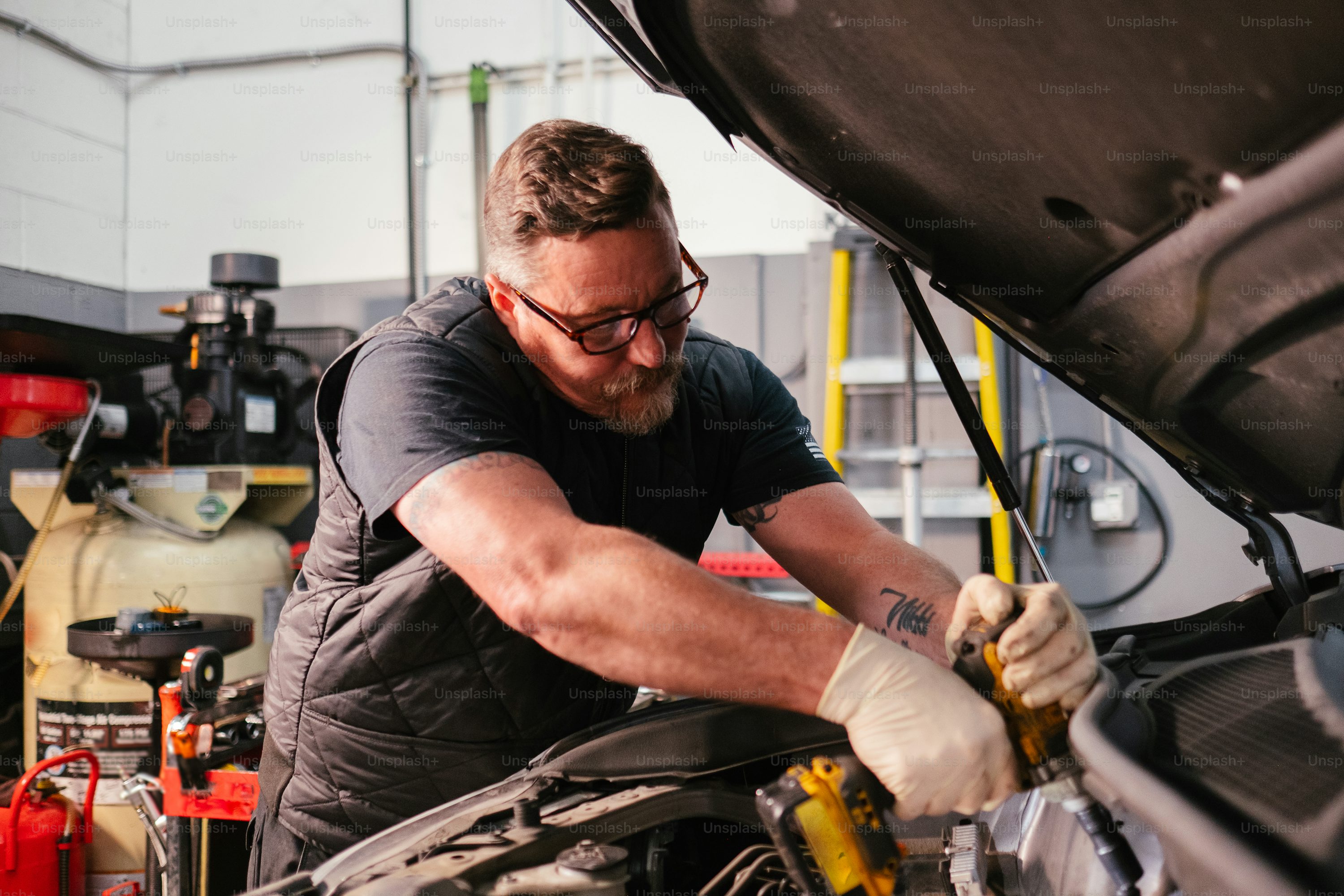 Auto repair mechanic working on a car engine in a garage workshop