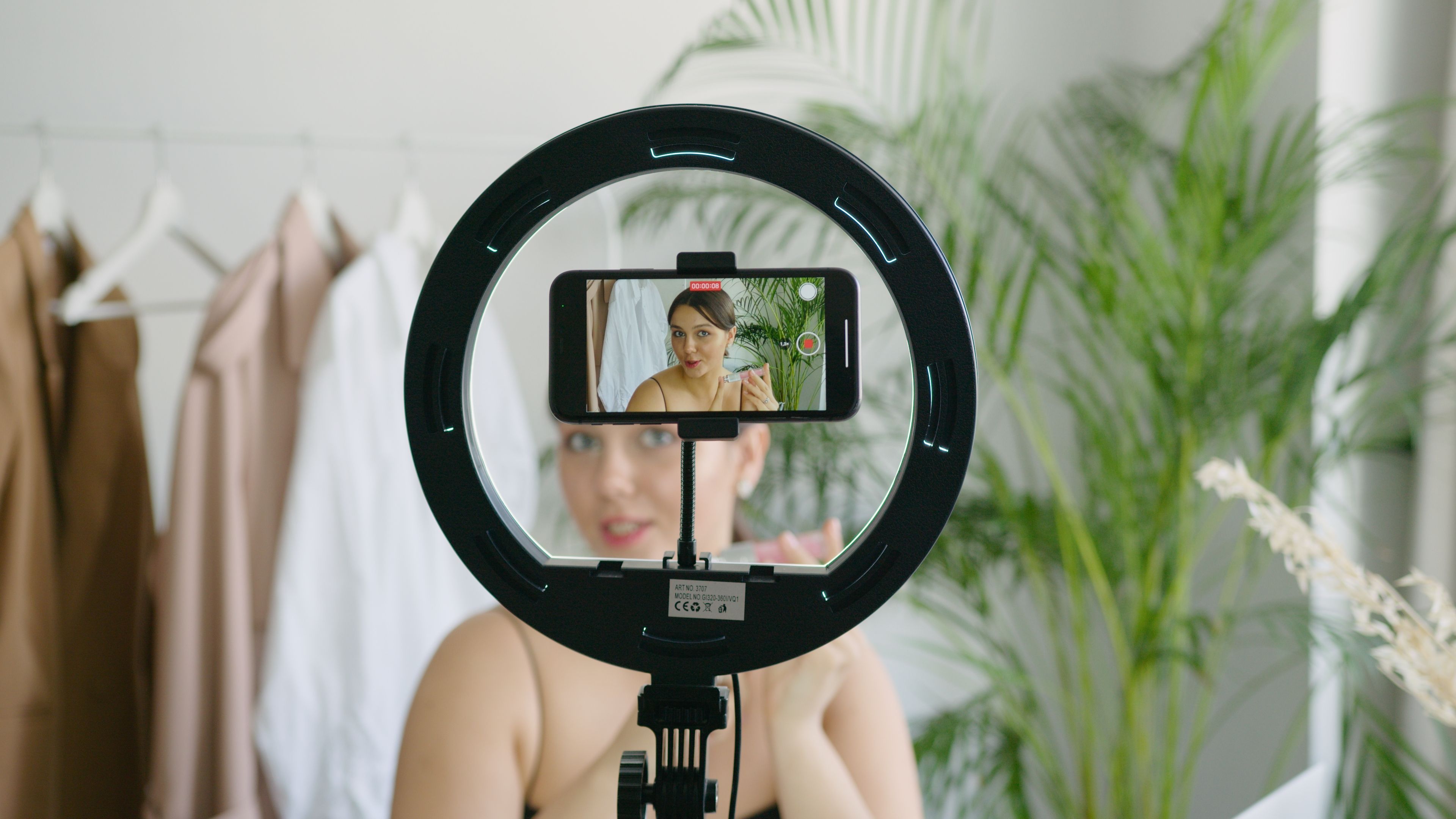 A creator filming a product review with a ring light, the format AI UGC ads now imitate with synthetic presenters