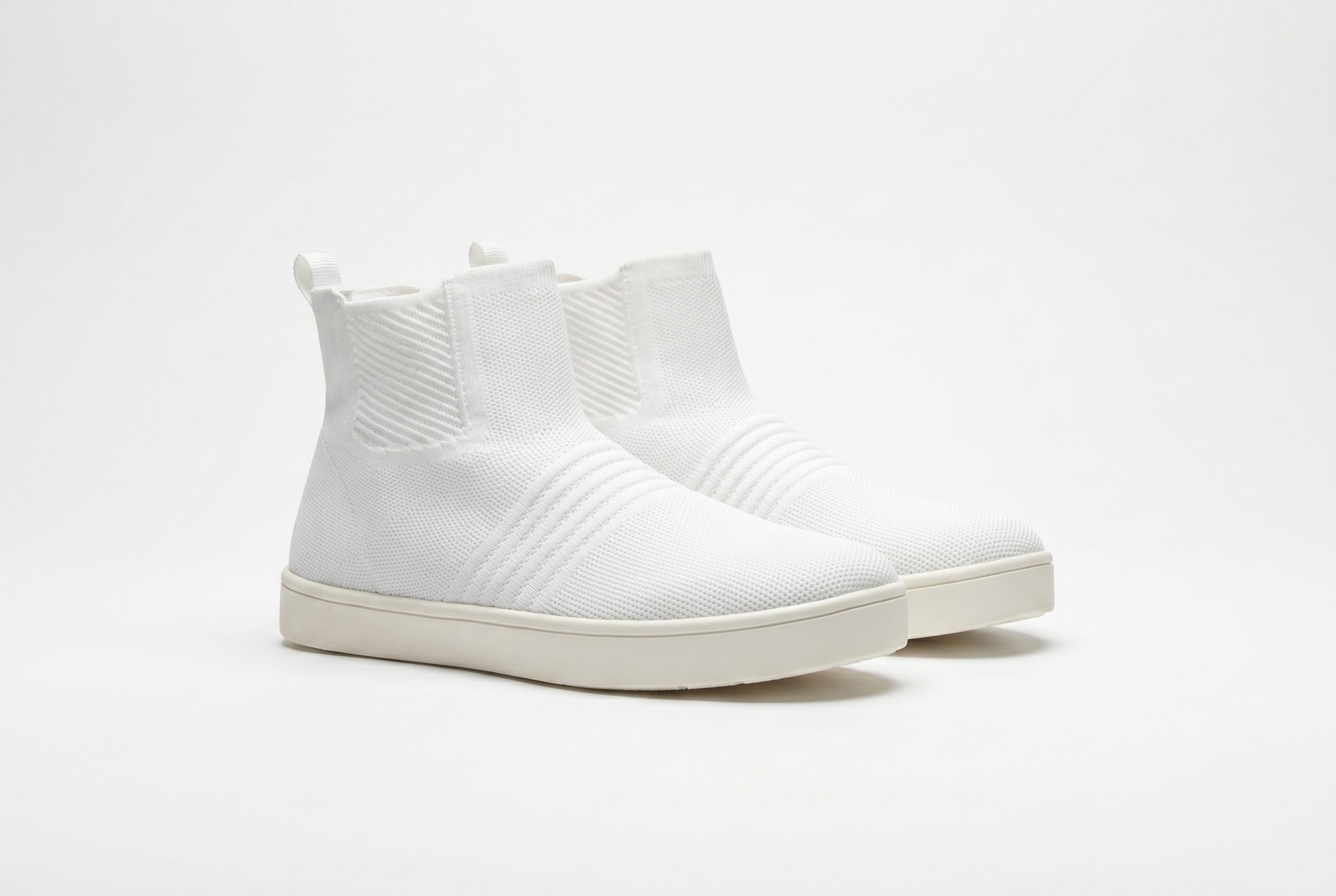 Clean studio product photograph of white sneakers on a neutral background