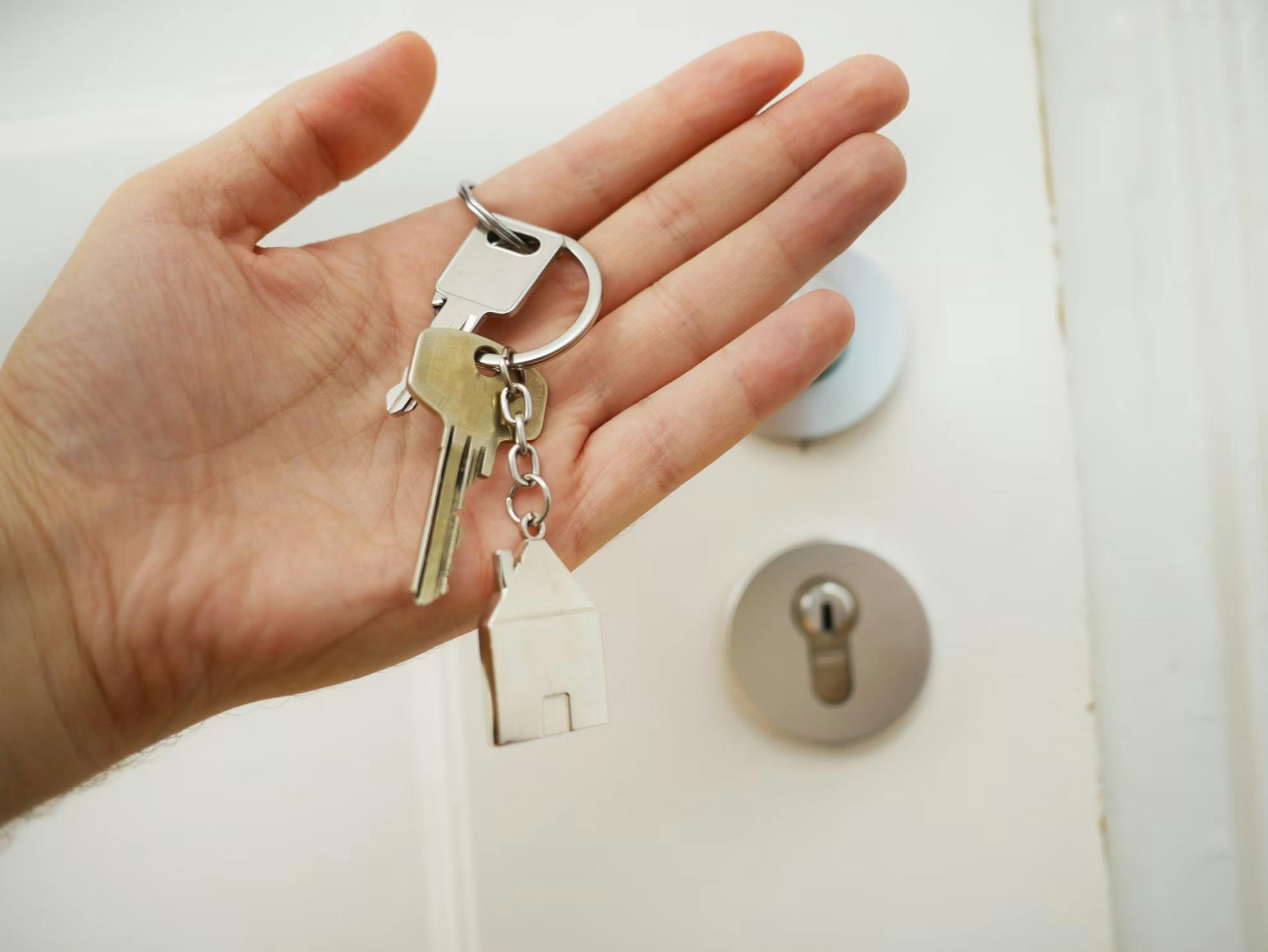 Wohnungsschlüssel mit Haus-Anhänger in einer offenen Hand