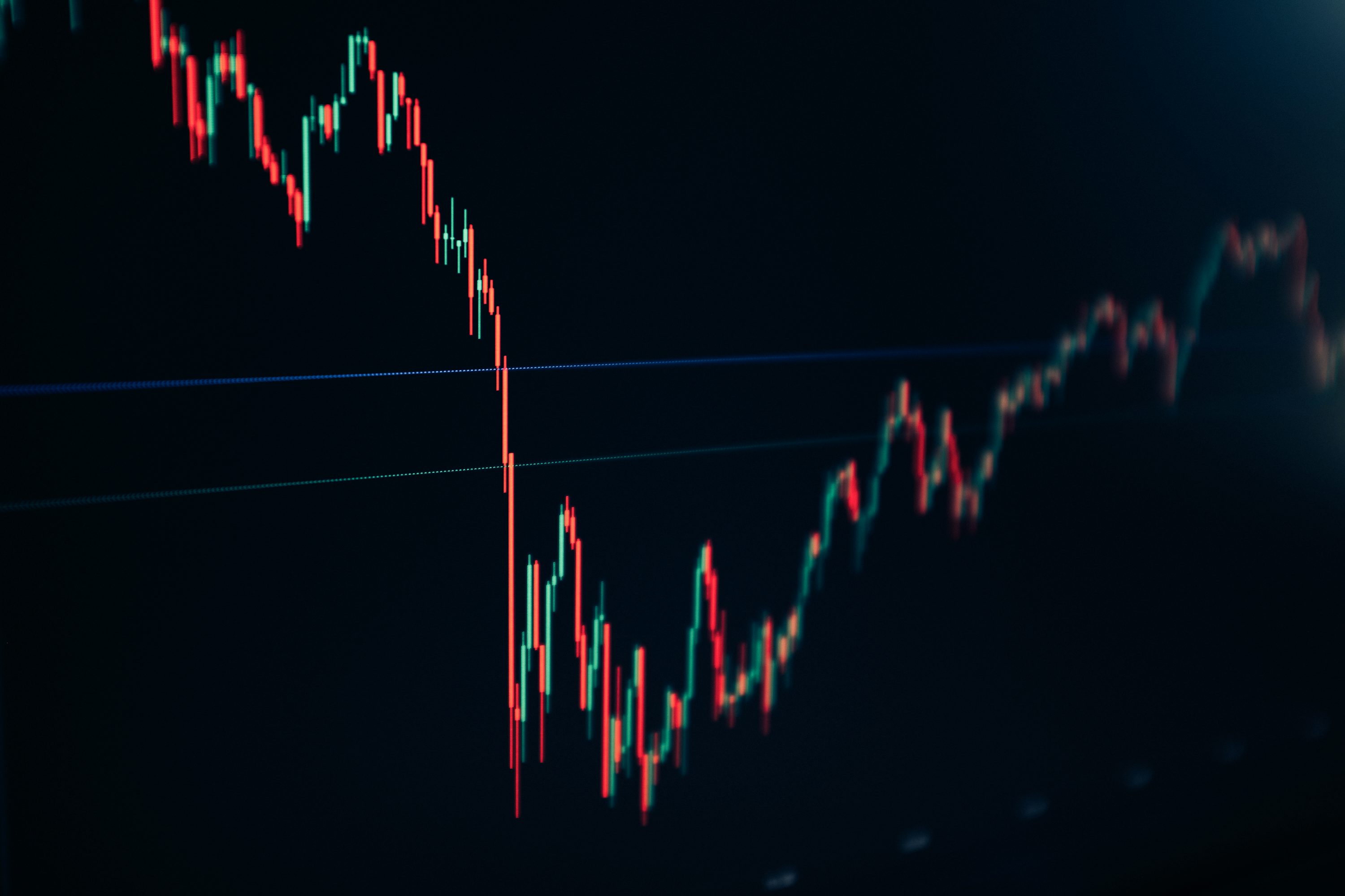Red and green candlestick history on a dark screen, the data every AI stock prediction model trains on