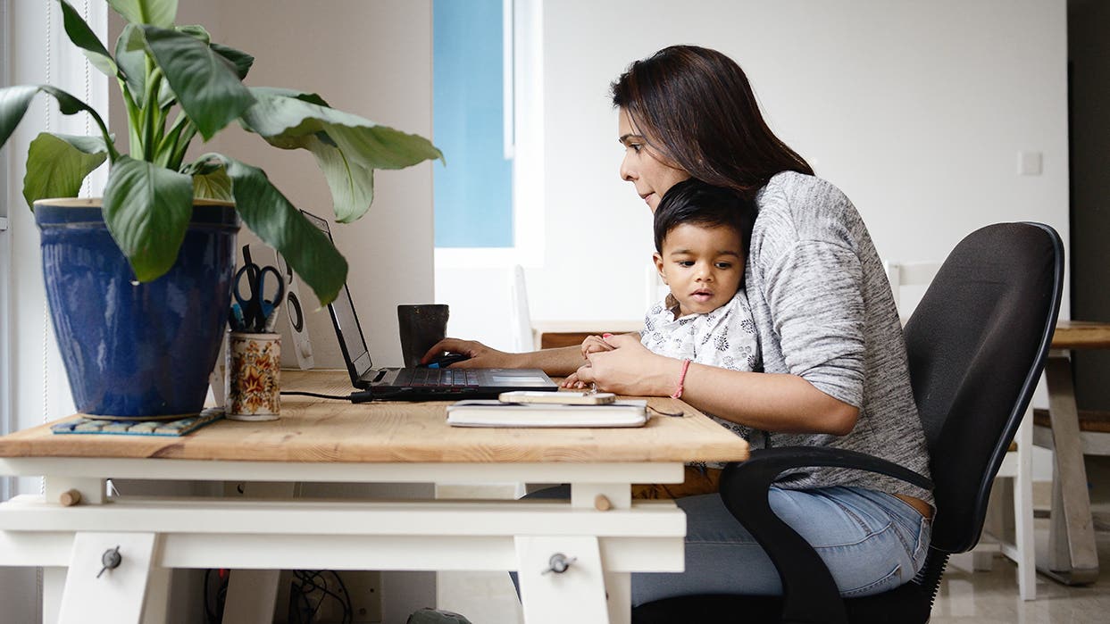 A parent working on family finances at a home desk, planning the household investment budget