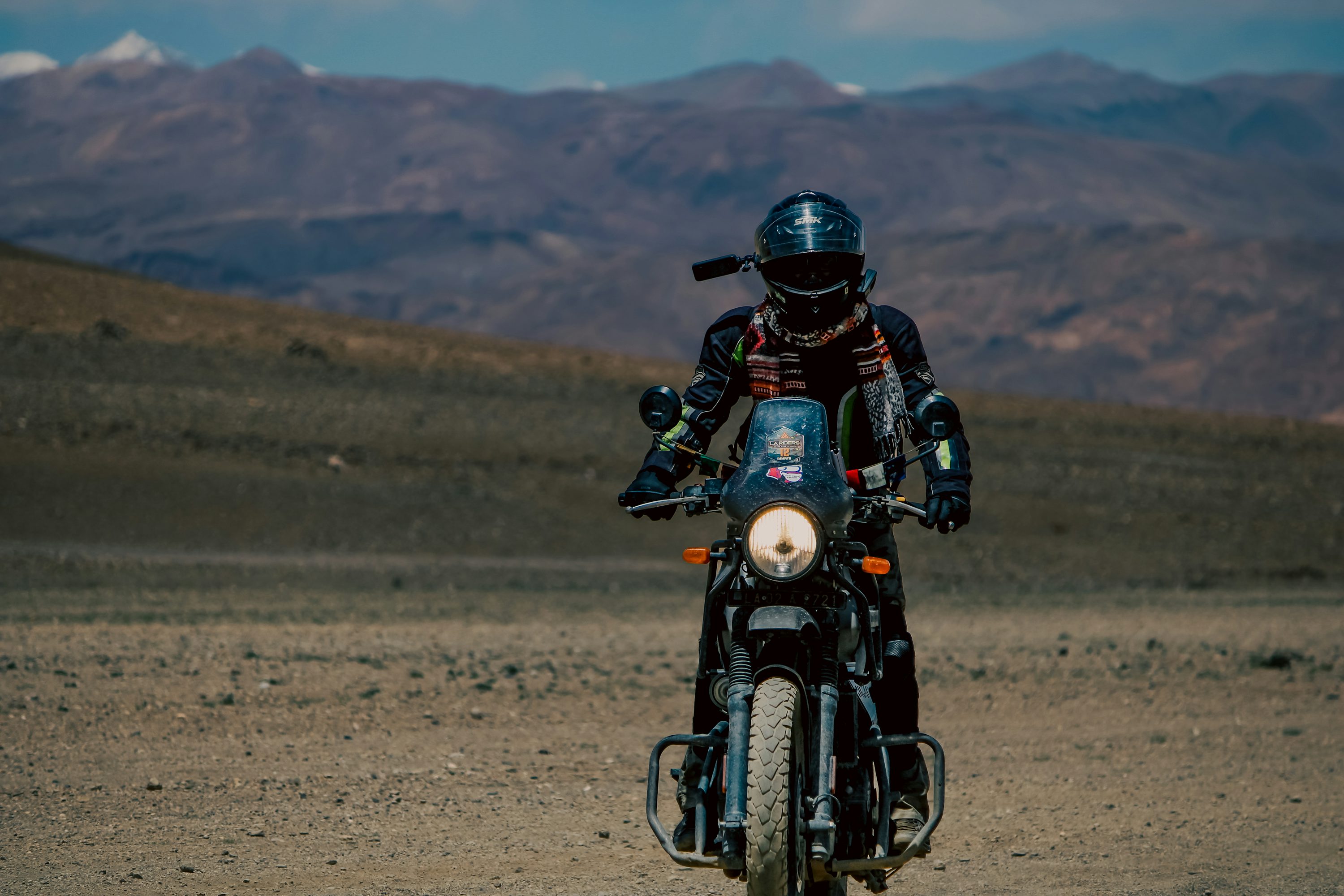 Motorcyclist on a Himalayan mountain road with peaks stretching into the distance