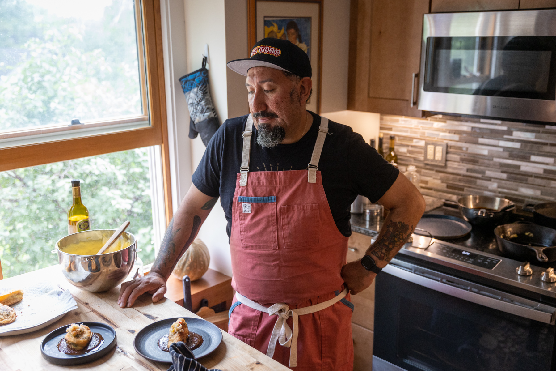 A cook in a red apron plating tacos in the truck