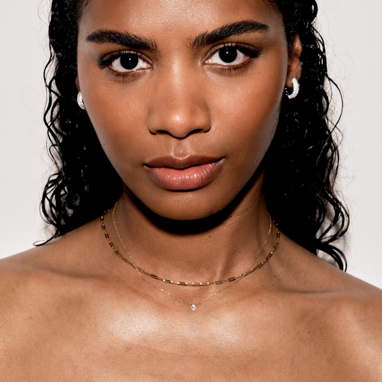 Close-up of woman wearing gold necklaces and diamond earrings