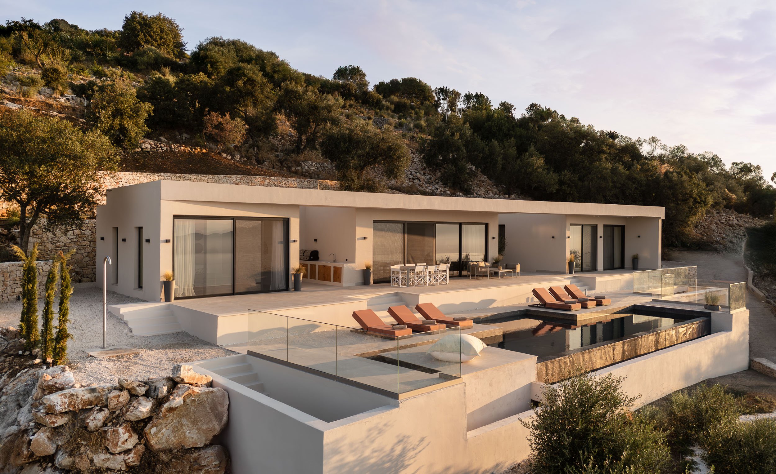 Minimalist white villa with infinity pool on a hillside