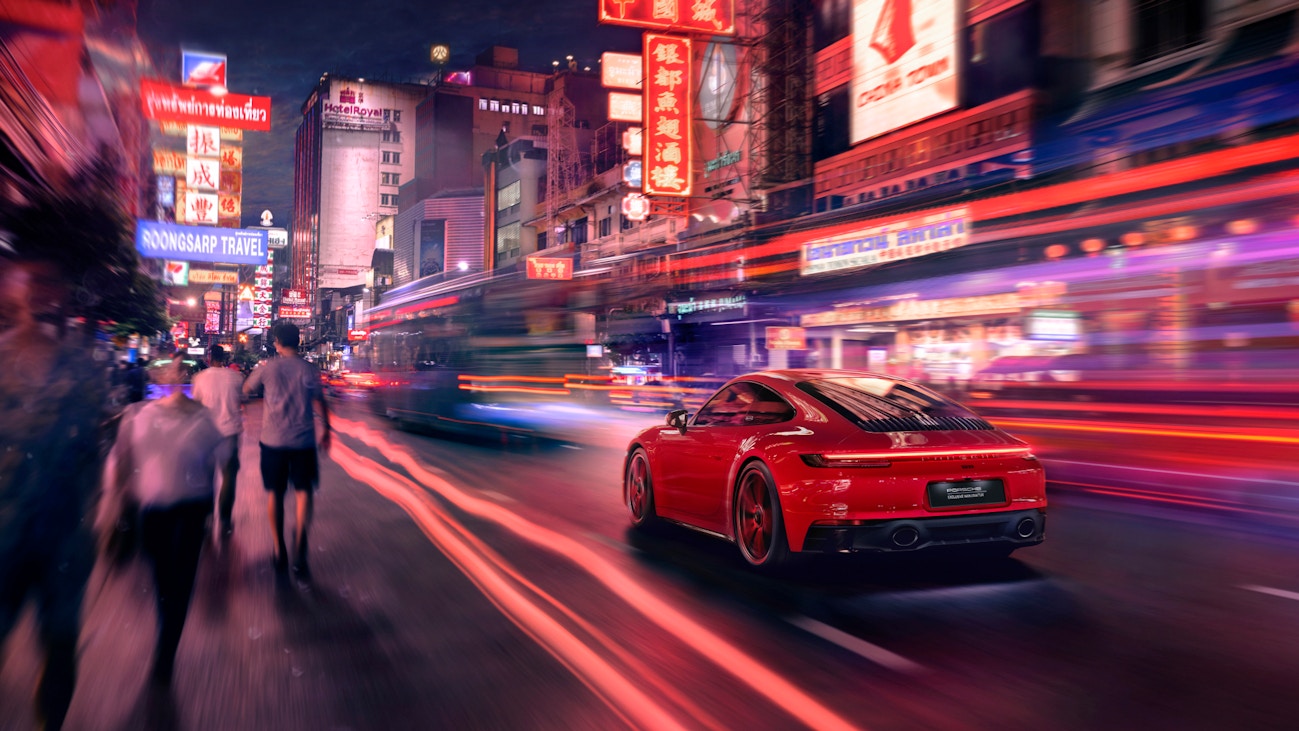 Red sports car driving through a neon-lit city street at night with motion blur