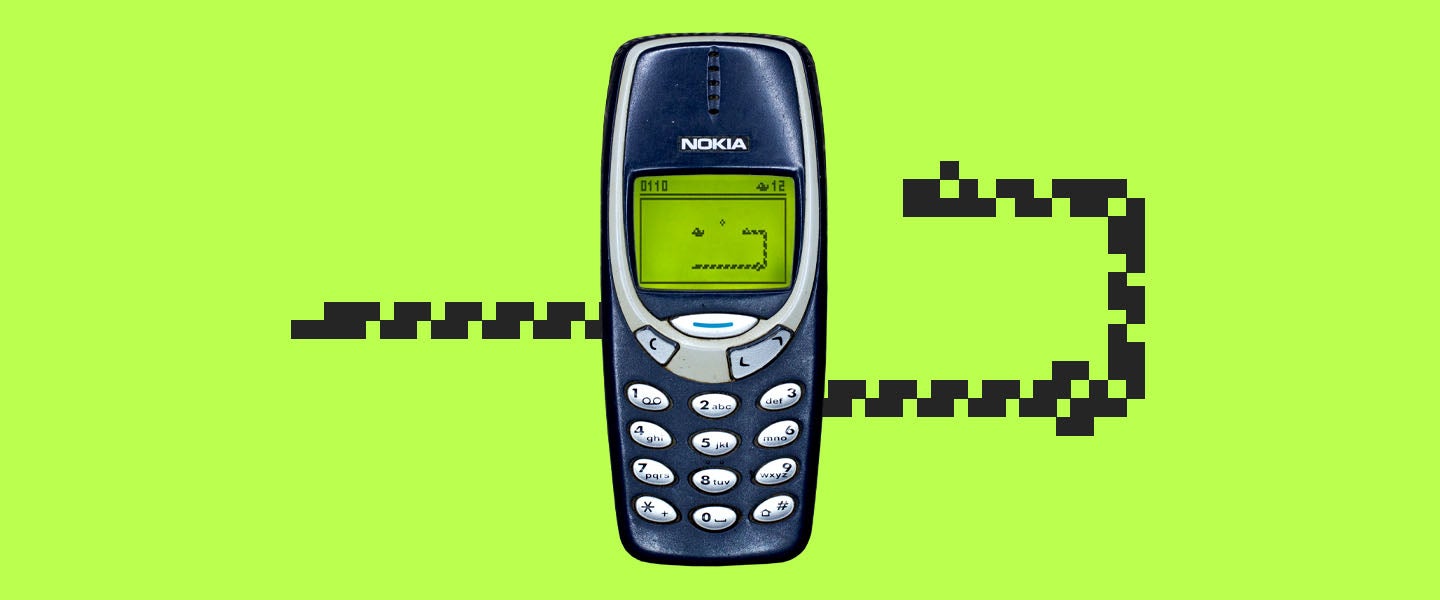 A Nokia 3310 mobile phone displaying the classic Snake game with a pixelated snake on its green screen