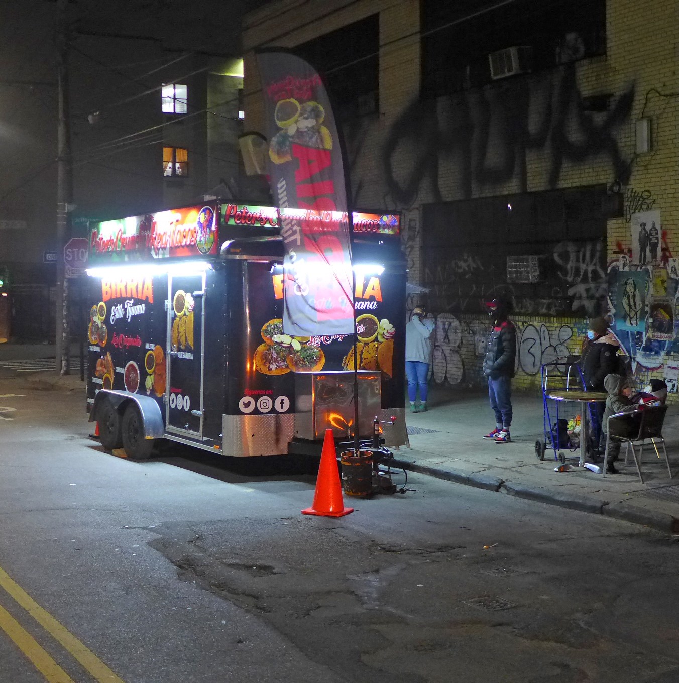 A lit taco food trailer glowing on an Austin street at night