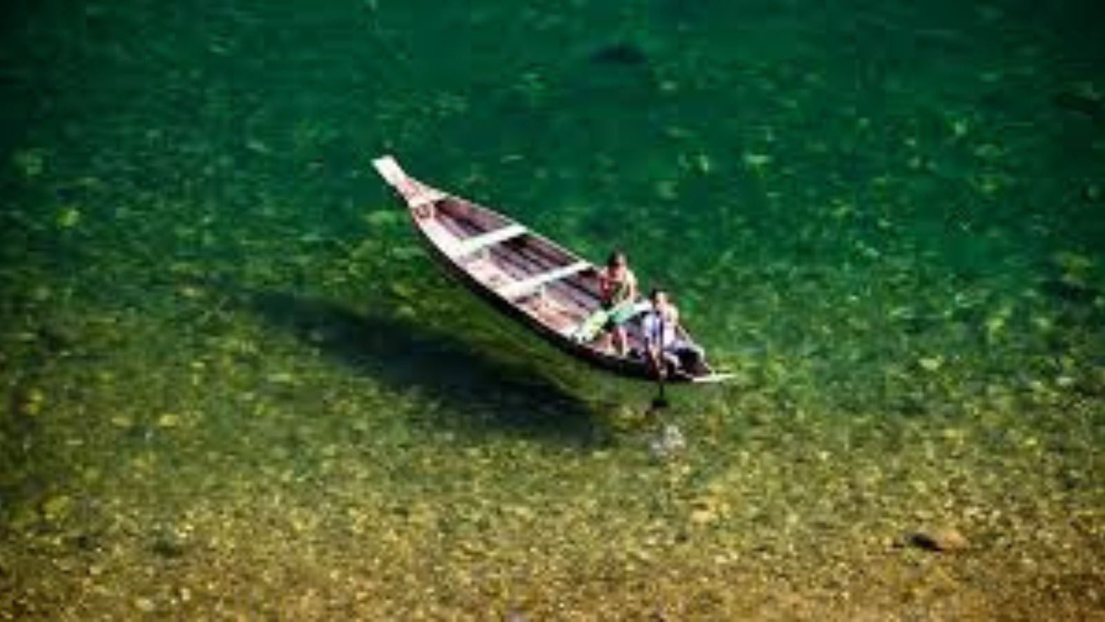 Wooden boat floating on the crystal-clear Umngot river at Dawki