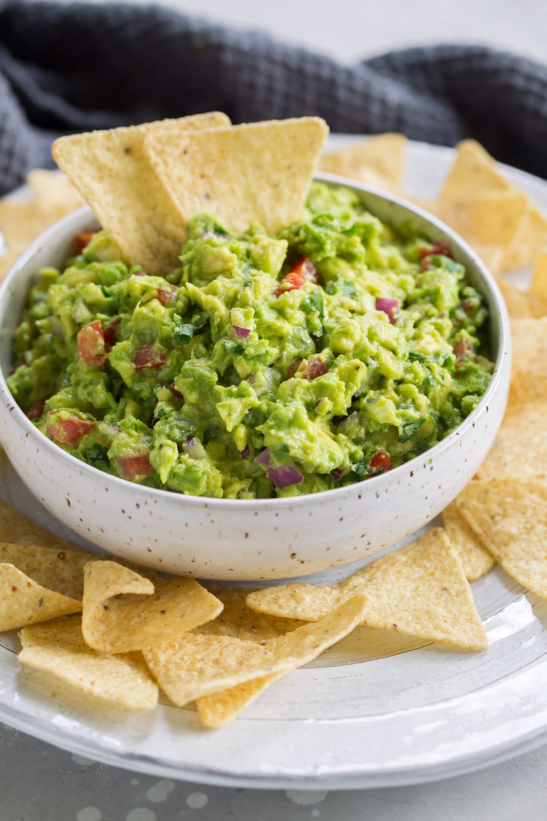 A bowl of fresh guacamole surrounded by tortilla chips