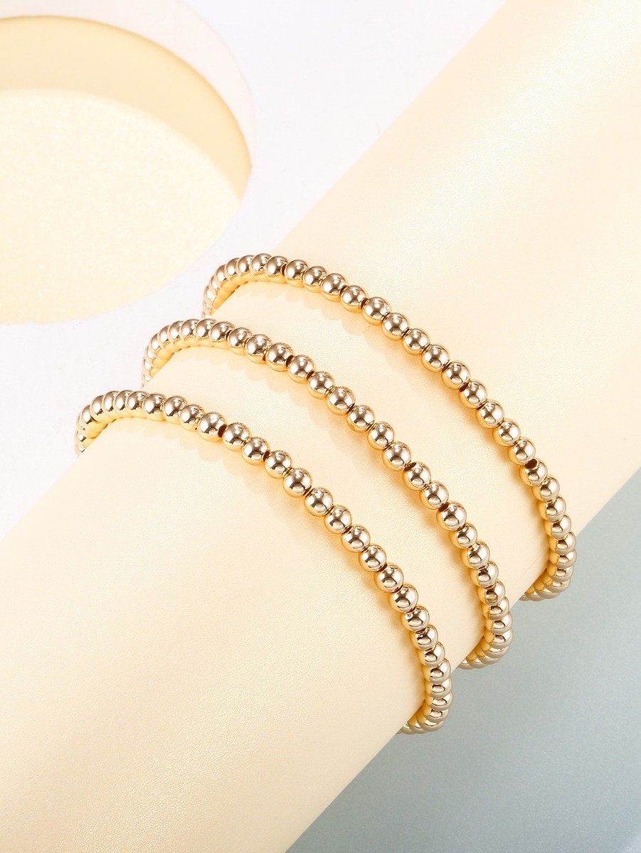 Noor beaded gold ball bracelets stacked on a cream display