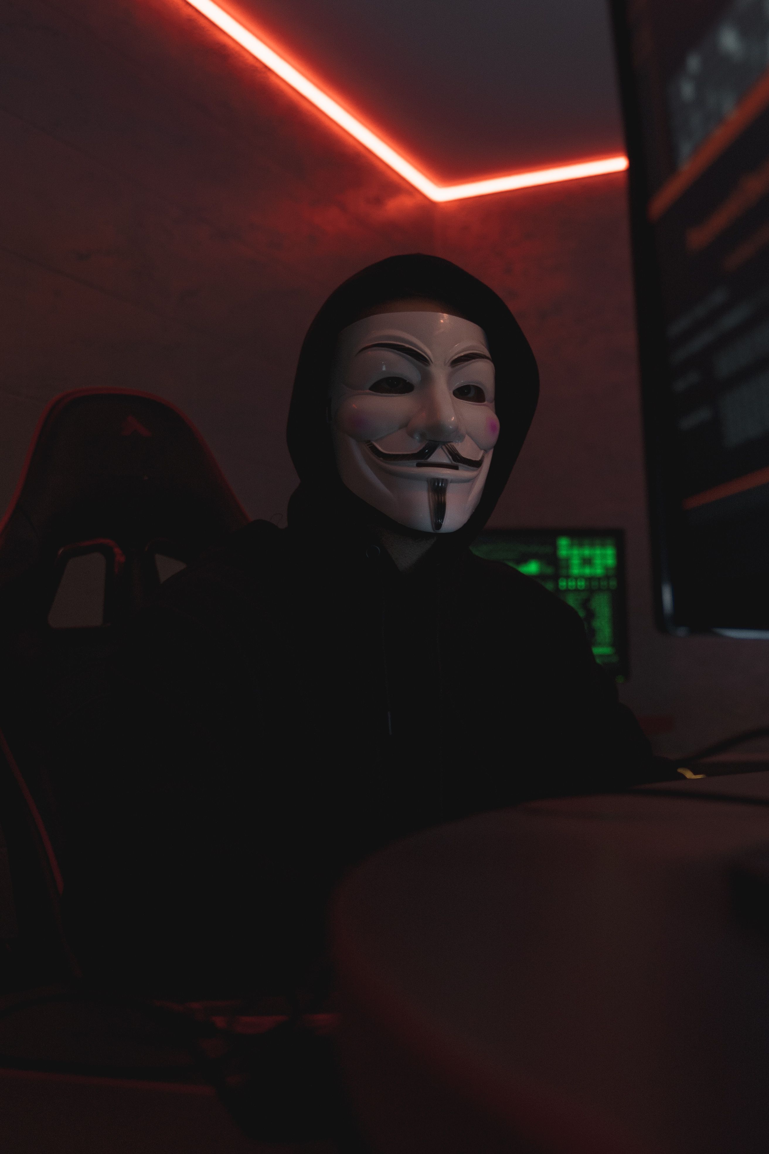 A person behind an anonymous mask at a keyboard, where cloned platforms are built overnight