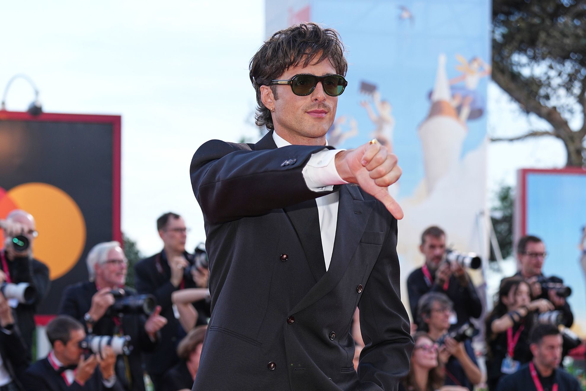 A celebrity surrounded by paparazzi camera flashes on a red carpet, the kind of famous face deepfake ads borrow without permission