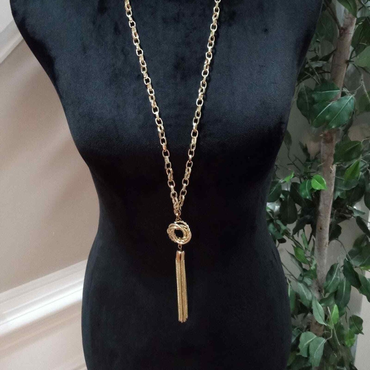 Cleo twisted circular pendant with tassel on a black backdrop