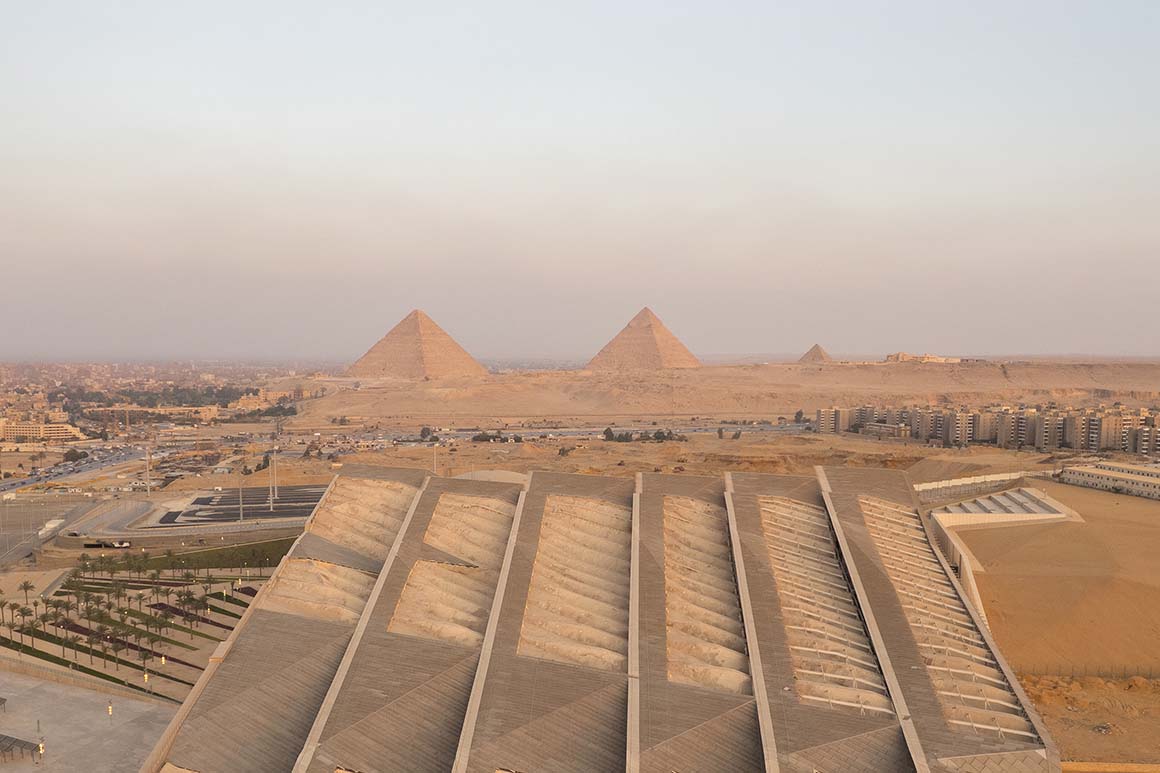 Exterior of the Grand Egyptian Museum in Giza with its triangular facade near the pyramids